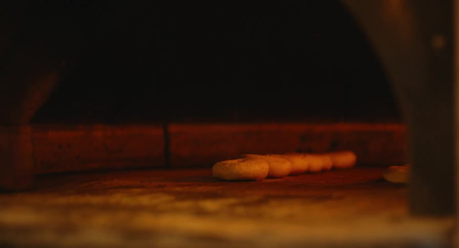 Baker taking fresh baked bagels out of the oven