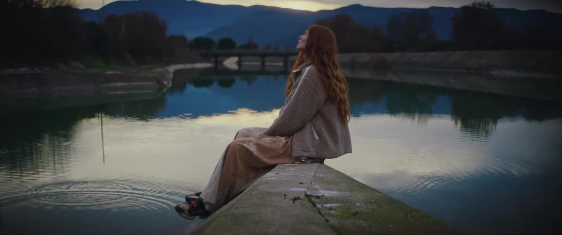 A woman sitting outdoors near a lake