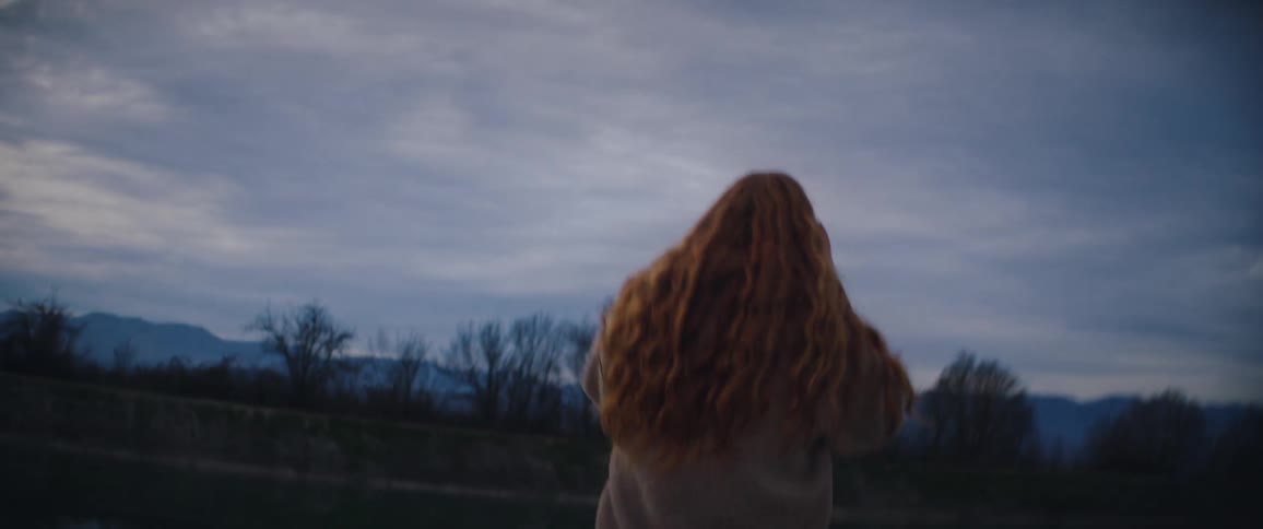 The woman is walking towards the lake