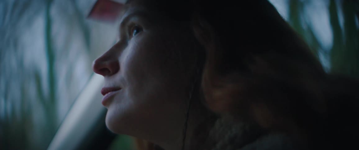 Young adult redhead woman looking out of the window of a car in motion indoors during dusk or dawn