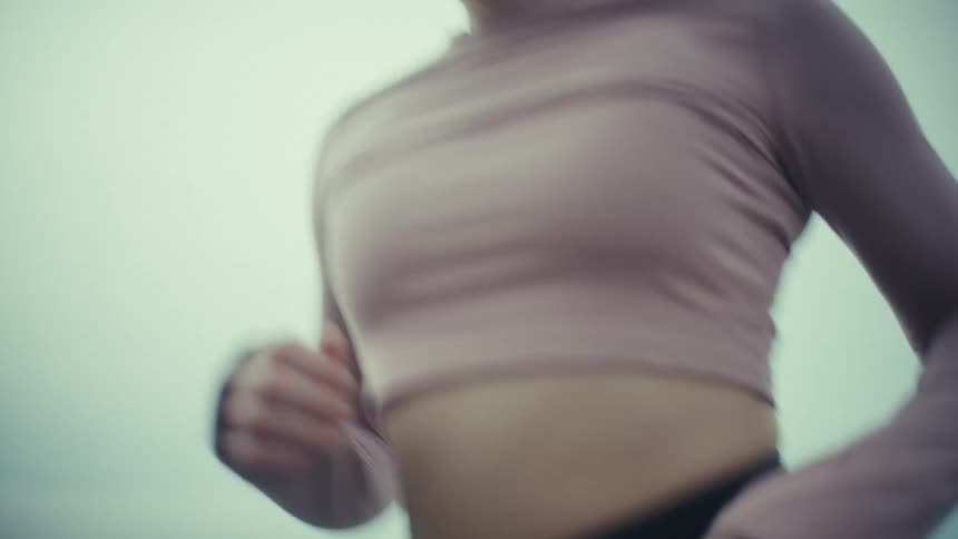 Woman runs up a staircase leading from a pedestrian path while jogging on a cloudy day