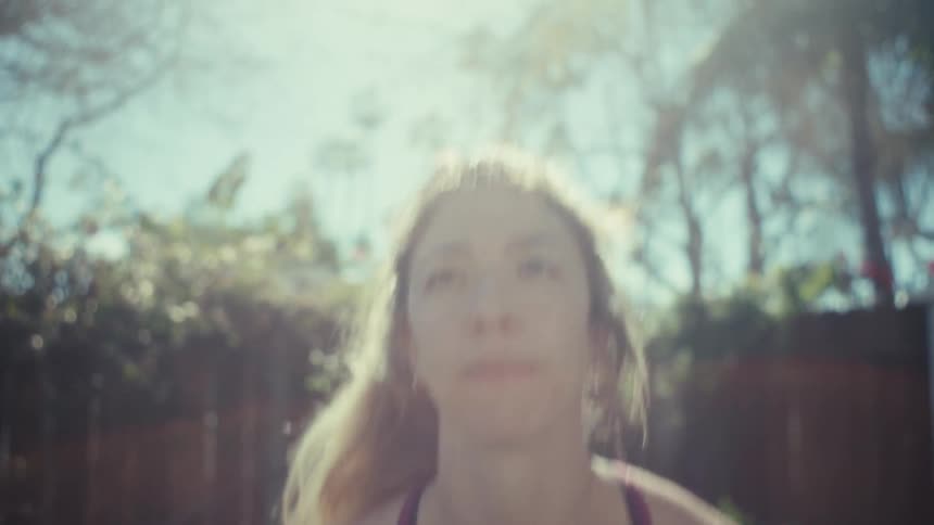 Adult woman in a lawn squatting while holding a kettle bell outdoors during day time