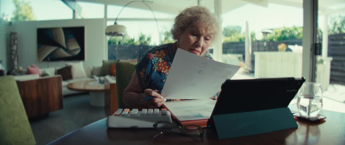 Woman sitting at a table with a tablet computer and calculator looking at paperwork