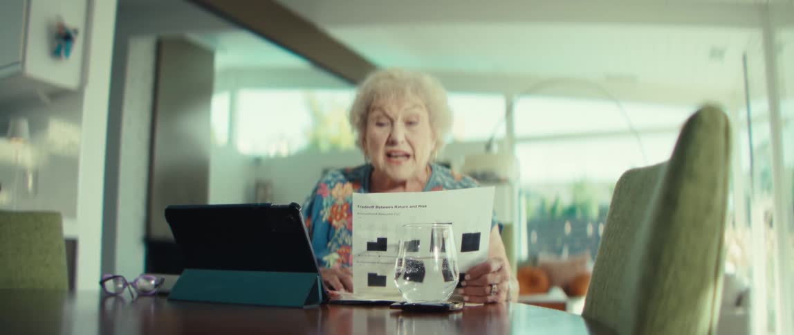 An elderly woman looks at some documents while talking aloud