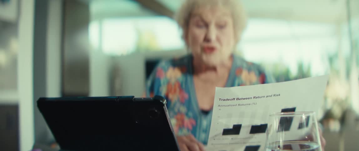 Elderly woman consults charts regarding tradeoffs between risk and return during a video call