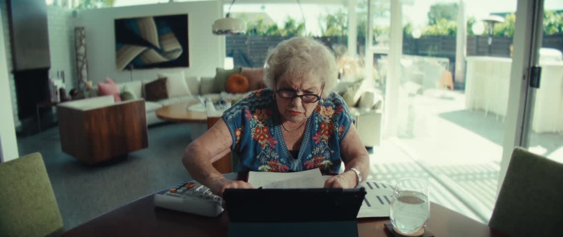 An elderly woman taps the screen of her tablet computer