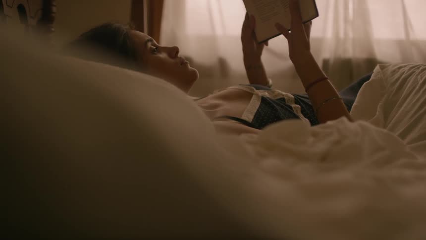 A woman is lying in bed reading a book