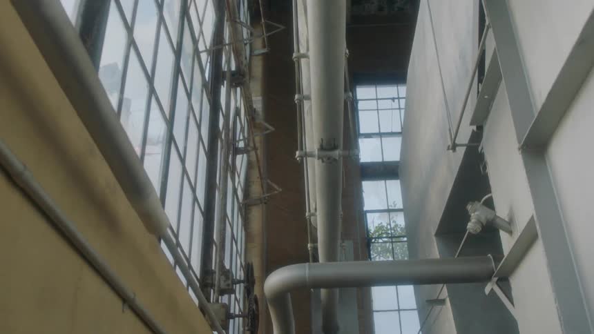 Industrial steel pipes hang over a walkway