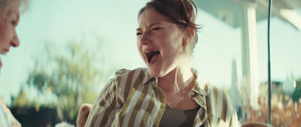 An elderly woman and a younger woman engage in a lively gaming session gripping controllers while displaying a range of intense joyful expressionsthe scene captures their dynamic interaction as they shout laugh and focus intently on the game togeth