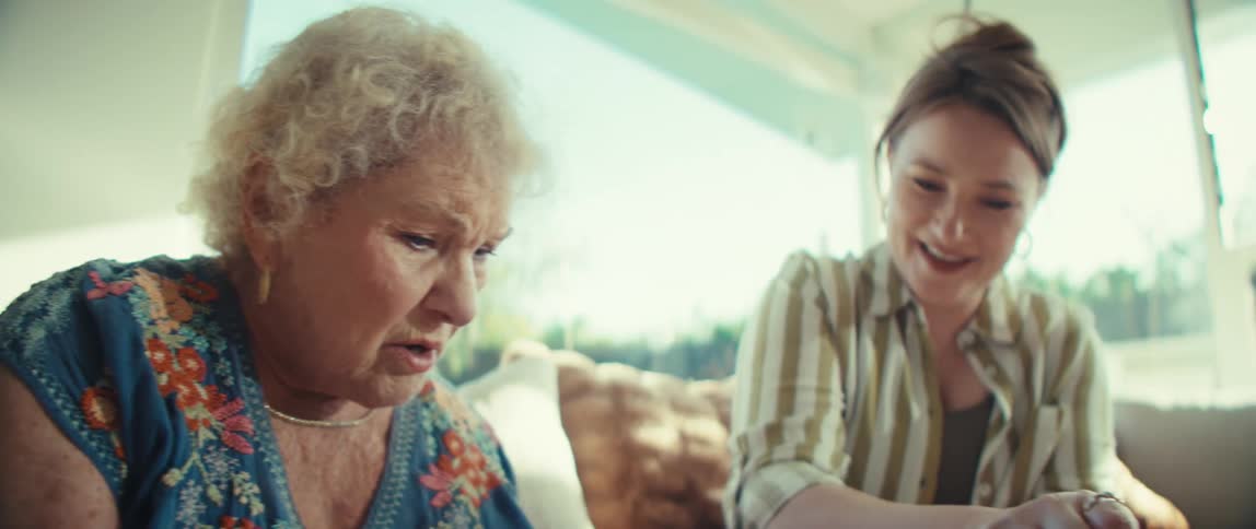 A mother and daughter having a fun conversation while sitting on a couch in a sunlit living room
