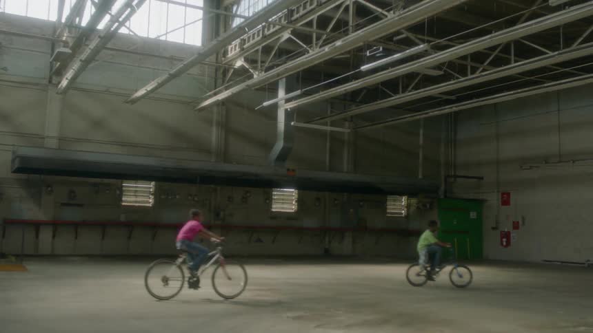 Group of kids riding bicycles inside empty warehouse