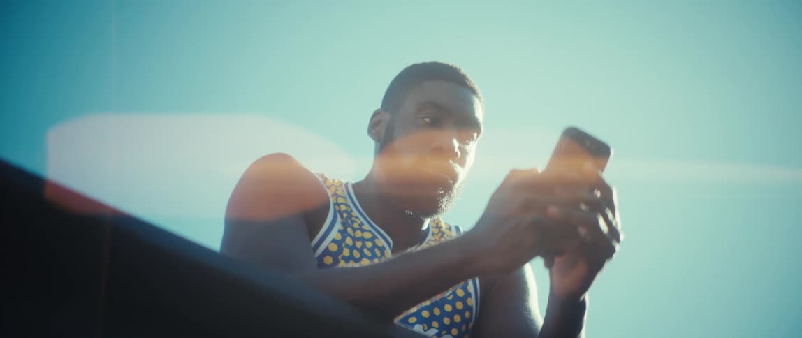 Man sits outside holding his phone with both hands while texting