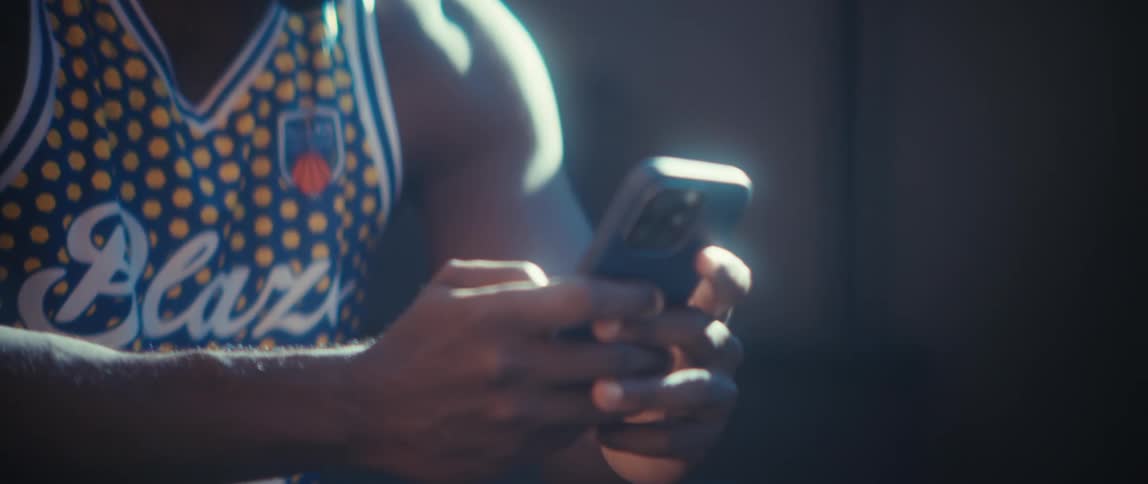 The man smiles while texting on his phone