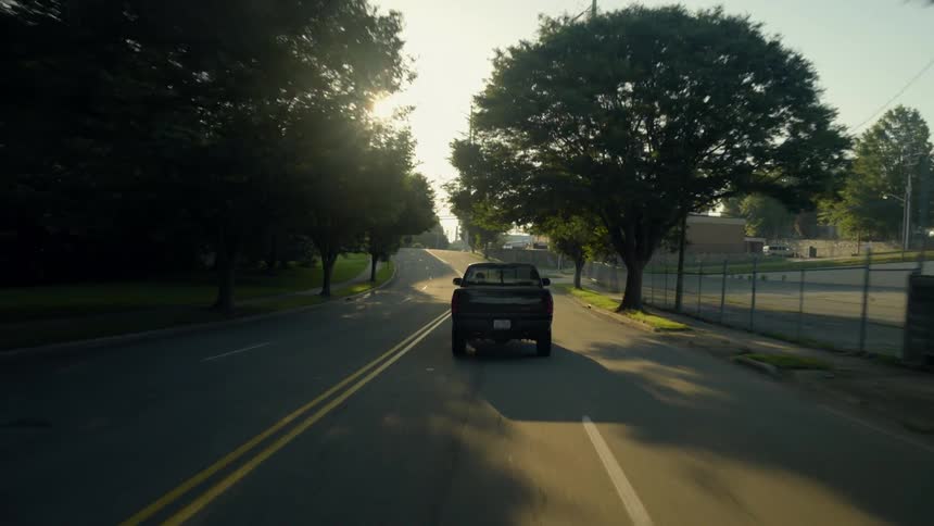 A truck drives down a tree lined road