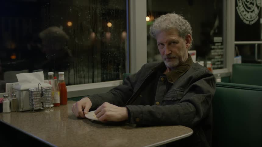 Man sitting and staring in restaurant booth at night