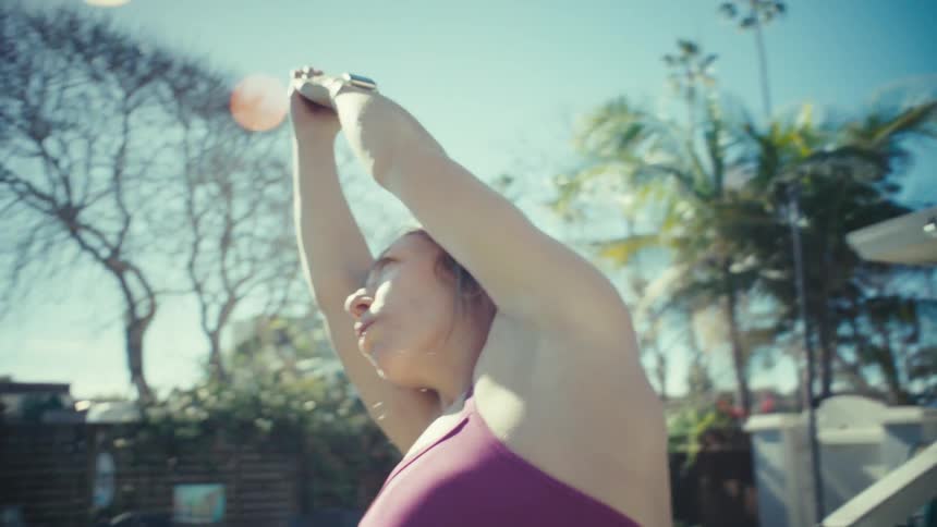 Woman exercising in front of a building with her arms in the air