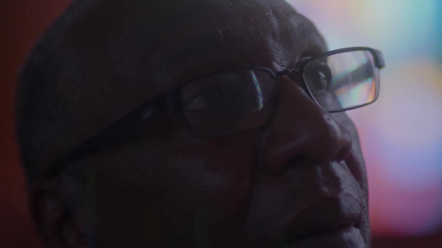 A man in glasses stares into the distance