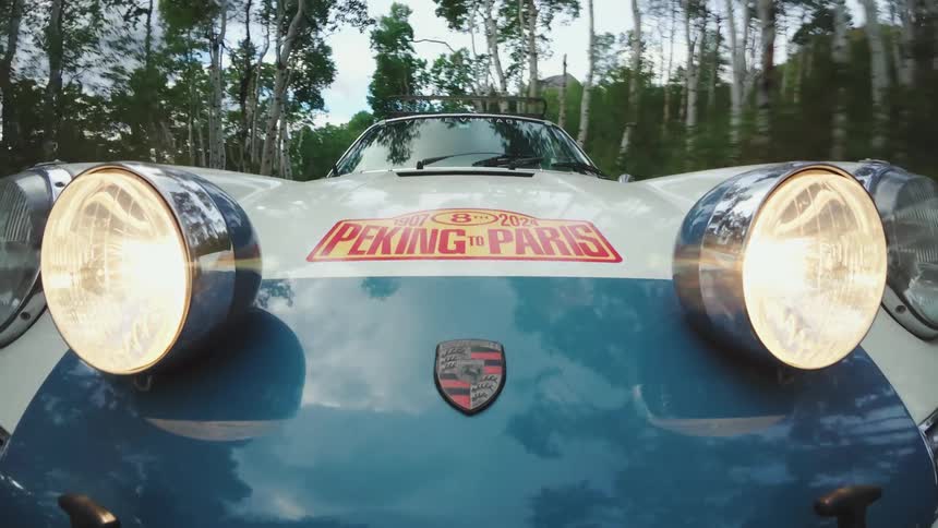 Car traveling on a road lined with trees and headlights on the hood