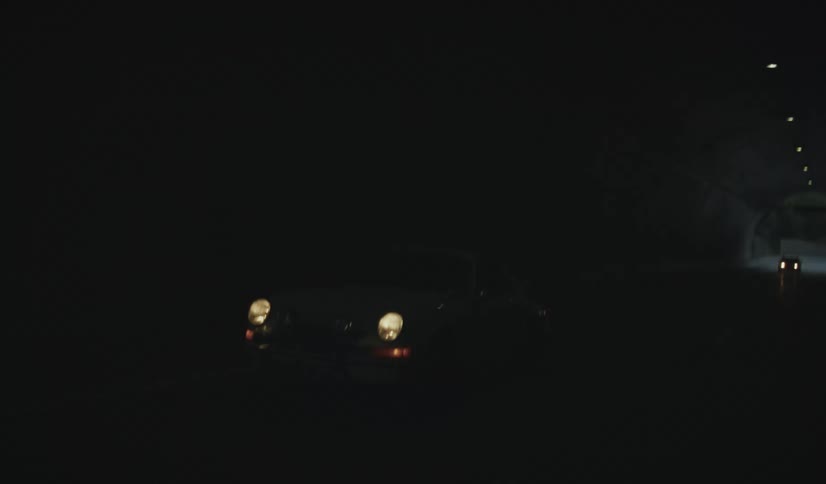 Vehicles drive along a highway passing through a tunnel in mountainous terrain after dusk