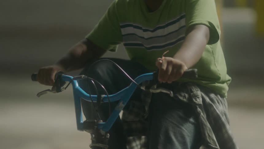 Kid riding bicycle in empty warehouse during the day