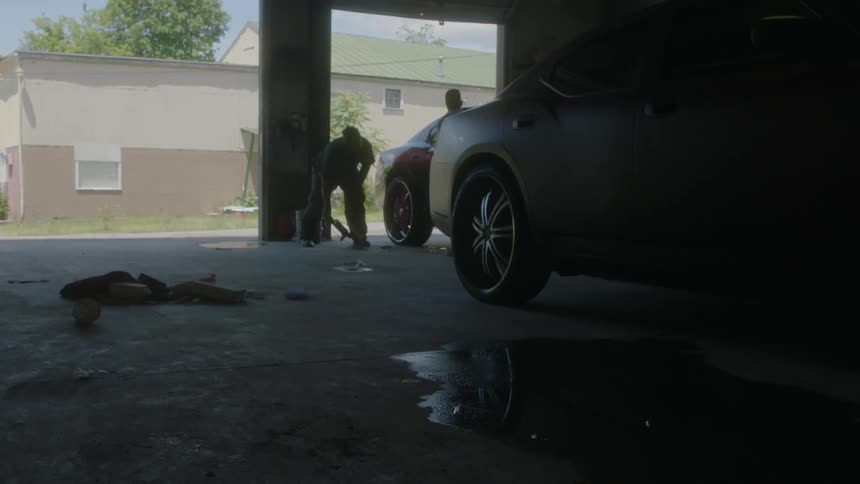 Two men work on a car in a garage