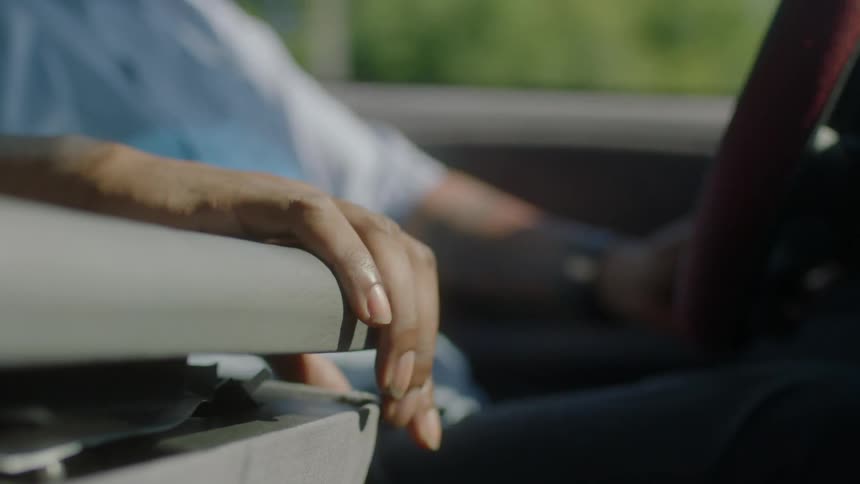 Hand resting on the middle console as a man drives