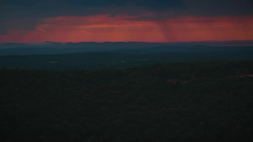 Orange sunset sky over forest and mountains