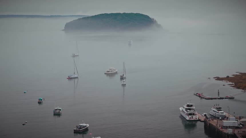 Boats anchored in a bay with a fogcovered island in the background