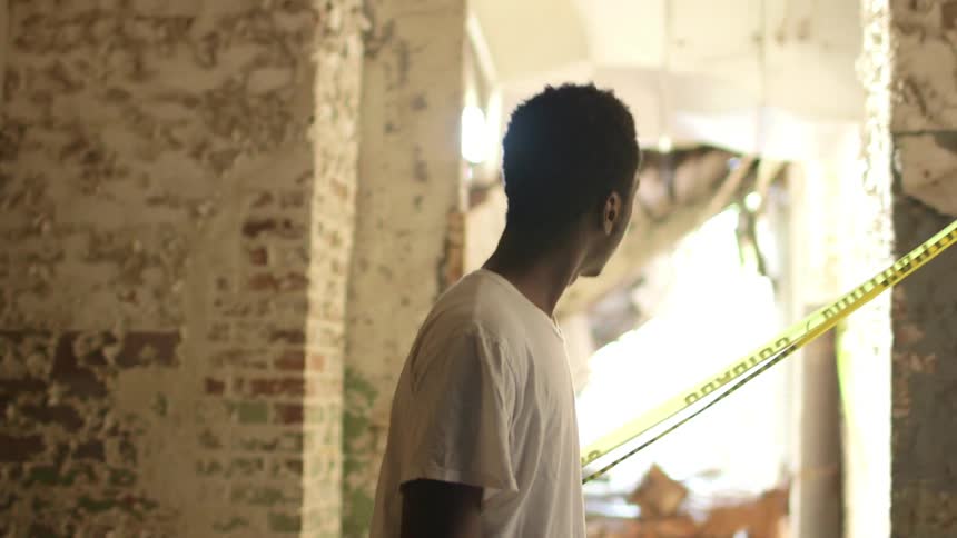 A young man in a white shirt wanders around