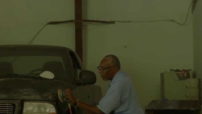 An older man is doing body work on a pickup truck