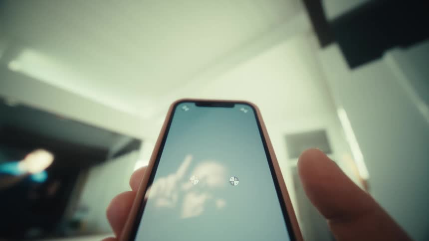 Smartphone screen reflecting a face held by hands indoors
