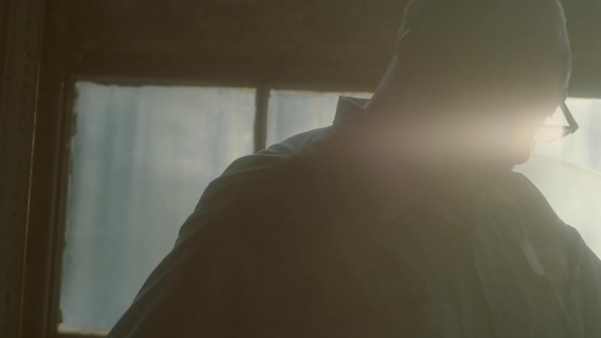 Sunlight shines through a window behind a man