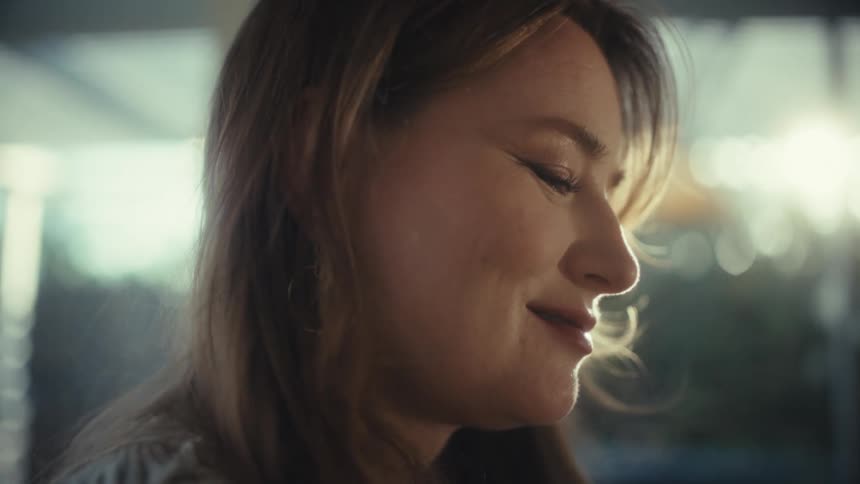 Young woman smiles and nods her head as she types on a laptop computer