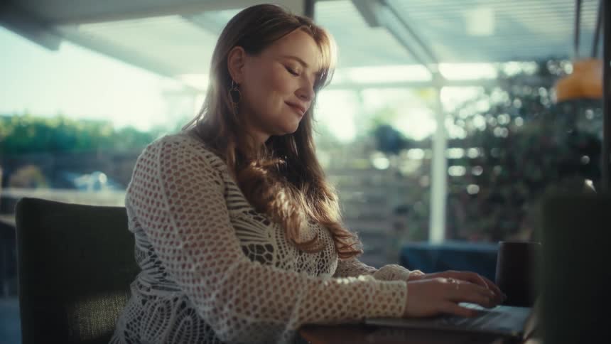 A woman sits in an office and types on a laptop