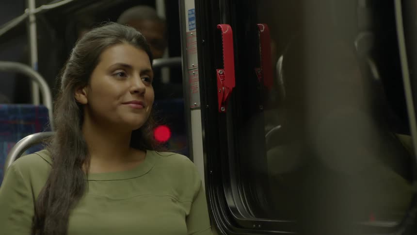 A woman is looking through her purse sitting on a train
