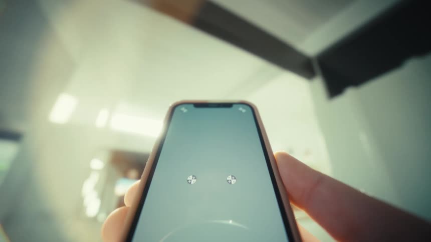 Hand holds smartphone showing two loading indicators on the screen indoors