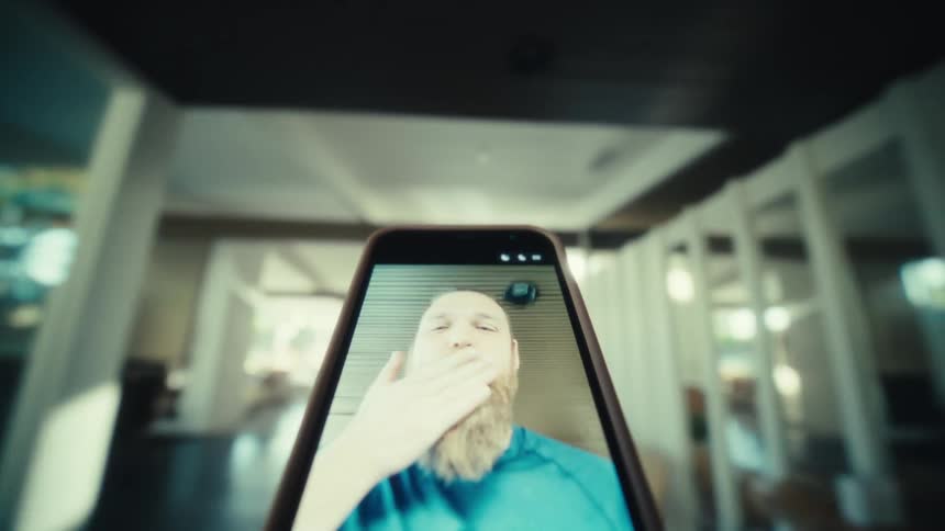 A man on a phone screen waves