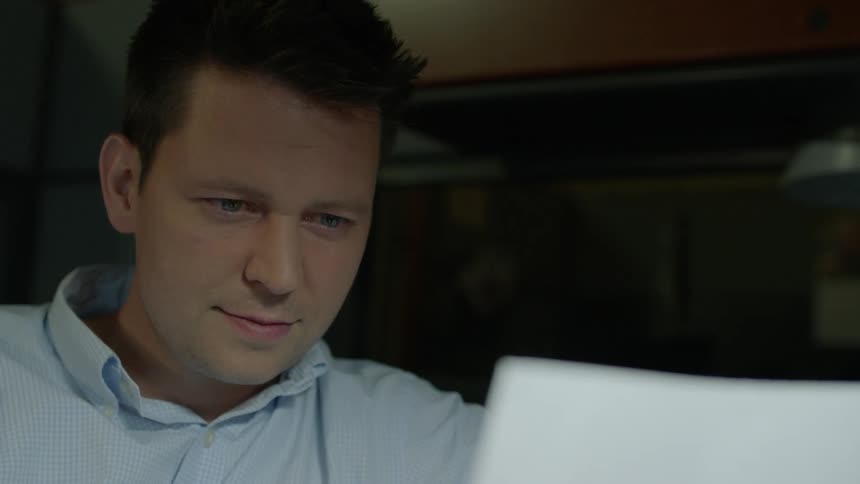 Man looking down at his laptop screen indoors