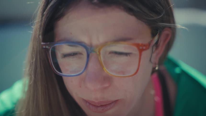 Woman wearing multicolored glasses looking downward in closeup