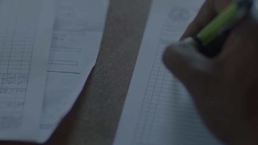 Person writing on a form on a table