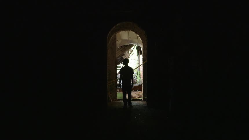 A boy walks near buildings and looks around
