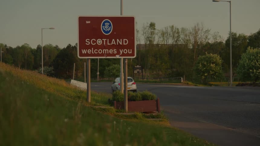 Scotland welcome sign positioned along a roadway with a vehicle in motion