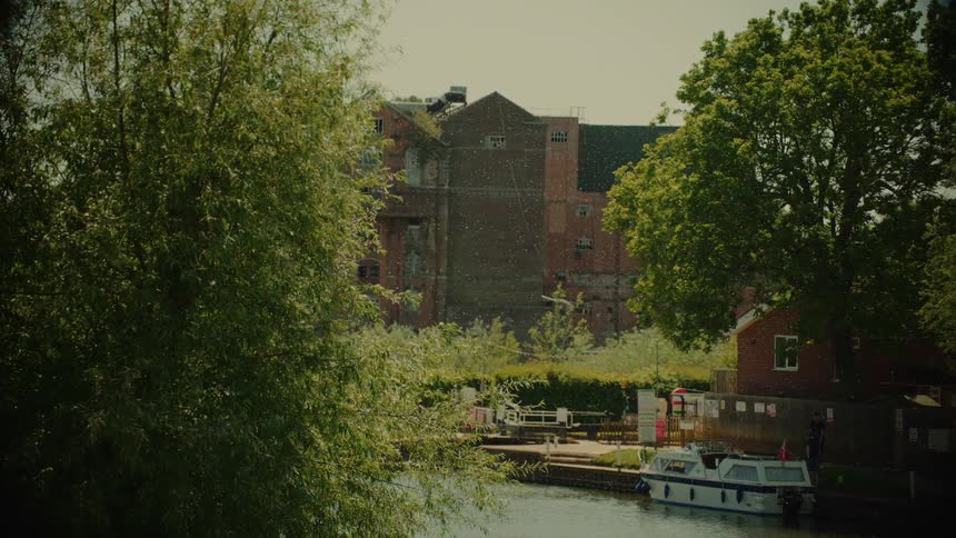 Urban canal with a moored boat in front of brick buildings surrounded by trees