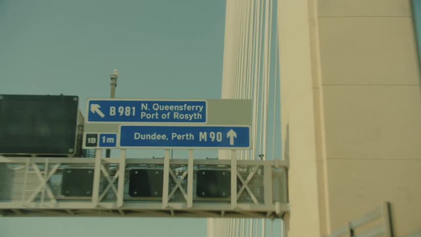 Road bridge with overhead directional signage and structural towers in the background