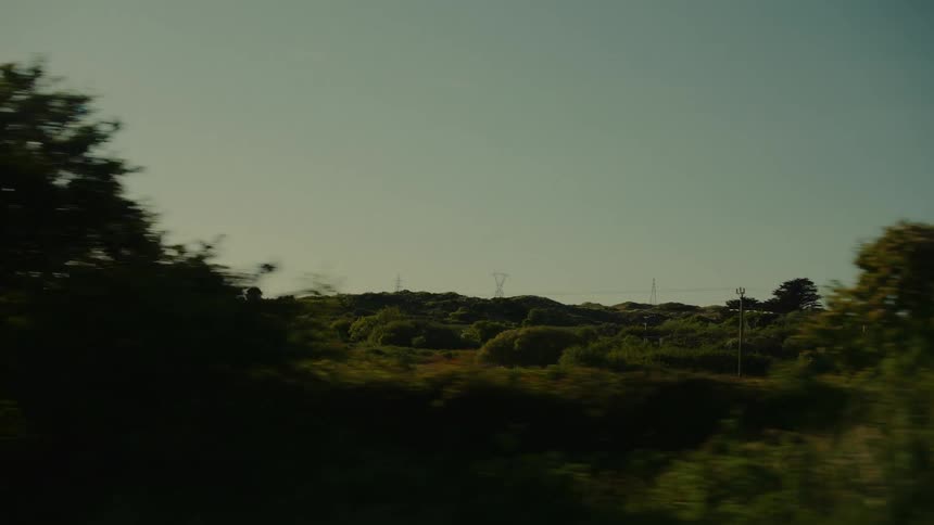 Rural landscape with dense vegetation and rolling hills under a clear sky
