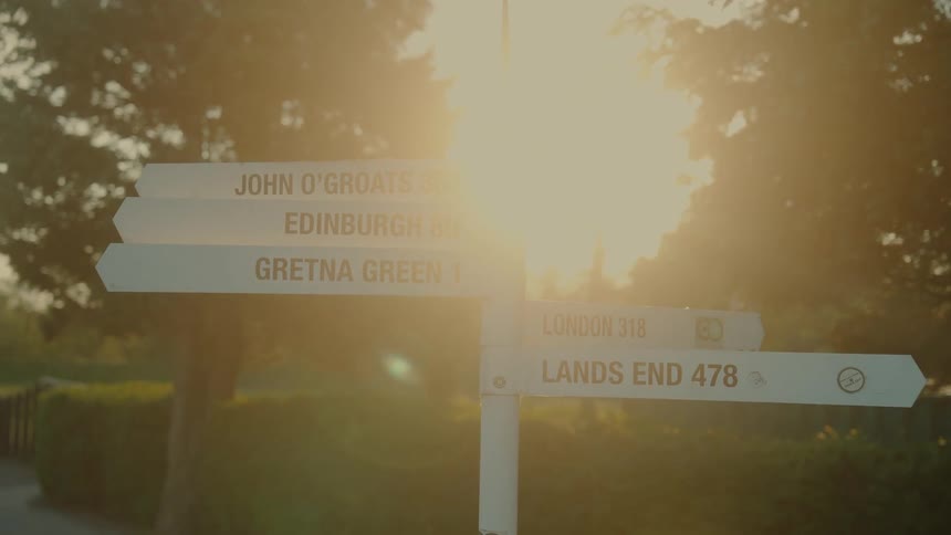 Road sign provides direction next to a country road on a sunny summer day