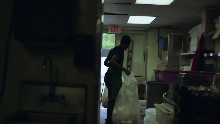Man in a workshop takes out two trash bags