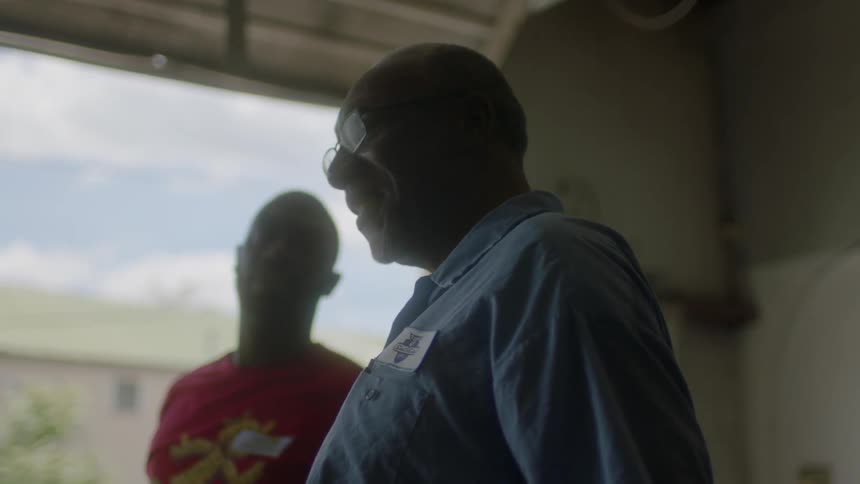 Two men stand talking in a garage