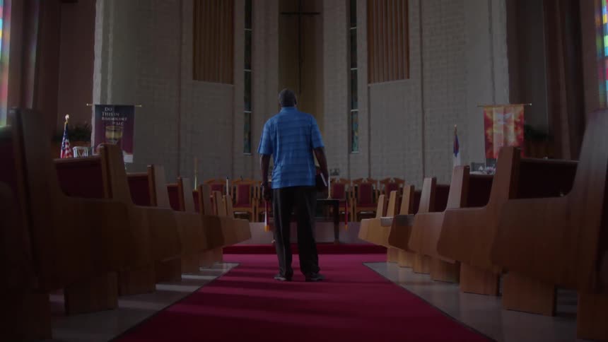 Man walks down the aisle of a church looking up