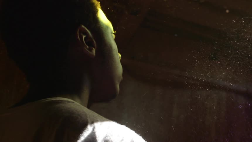 Man standing indoors with beams of light showing the dust in the air